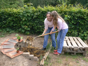 zwei Schlerinnen arbeiten gemeinsam im Schulgarten