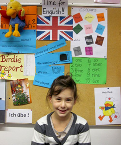 Das Foto zeigt ein Mädchen vor einer Plakatwand zum Englisch-Lernen.