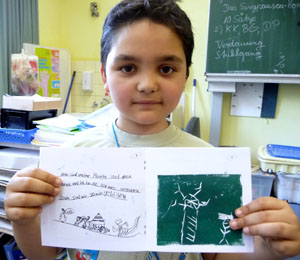 Das Foto zeigt einen Jungen, der ein Buch präsentiert, welches er selbst gemacht hat.