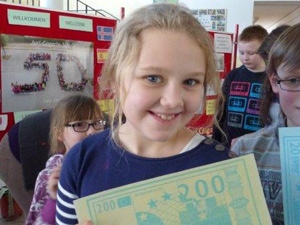 Das Foto zeigt ein lachendes Mädchen, das eine Kopie eines 200-Euro-Scheins in der Hand hat. Was man nicht sieht: Dieser Schein besteht aus essbarem Papier.