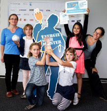 Das Foto zeigt vier Schülerinnen, ihre Lehrerin und eine Mitarbeiterin des Umweltbro Nord eV, die vor dem Logo Energiesparmeister posieren.