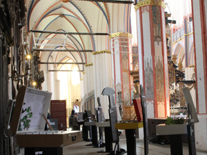 Das Foto zeigt das Innere einer groen gotischen Kirche, im Vordergrund sind einige Ausstellungsexponate - groe Koffer auf Tischchen - zu sehen.