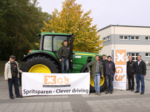 Das Foto zeigt eine Gruppe von Berufsschülern mit ihren Lehrern vor einem groen John-Deere-Traktor mit einem Banner: Clever Driving.