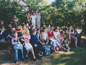 Schüler sitzen auf Baumstämmen zum Gruppenfoto