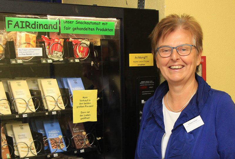 Das Foto zeigt eine Frau vor einem Verkaufsautomaten für Fairtrade-Snacks.