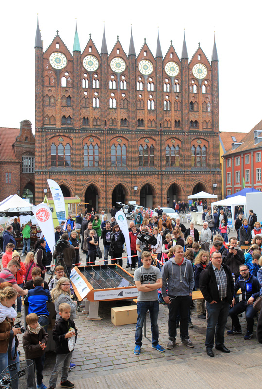 Das Foto zeigt viele Menschen, die auf dem Alten Markt in Stralsund stehen und der Verleihung des Stralsunder UMweltpokals zusehen. Im Hintergrund ist das Rathaus der Hansestadt zu sehen.