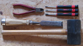Das Foto zeigt Werkzeug: Zange, Schraubendreher, Stechbeitel und Gummihammer.