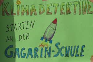 Das Foto zeigt ein Plakat mit der Aufschrift Klimadetektive starten in der Gagarin-Schule sowie einer Weltraumrakete