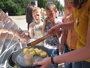 Das Foto zeigt Schüler der Gagarinschule vor einem Solarkocher, auf dem Maisscheiben gedünstet werden.
