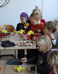Das Foto zeigt Kinder, die Wärmeräder aus Papier bauen und diese - wie Weihnachtspyramiden - mit Kerzen zum Drehen bringen.