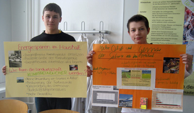 Das Foto zeigt zwei Schüler mit ihren Postern zu Energiesparen im Haushalt bzw. klimafreundlicher Ernährung.