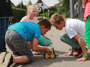 Das Foto zeigt drei Kinder, die ein solar angetriebenes Modellfahrzeug testen.