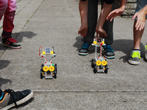 Das Foto zeigt zwei solar angetriebene Modellfahrzeuge, die von Kindern auf ihrem Schulhof getestet werden.