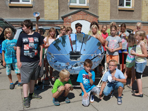 Das Foto zeigt Schüler, die im einen Solarkocher herum stehen.