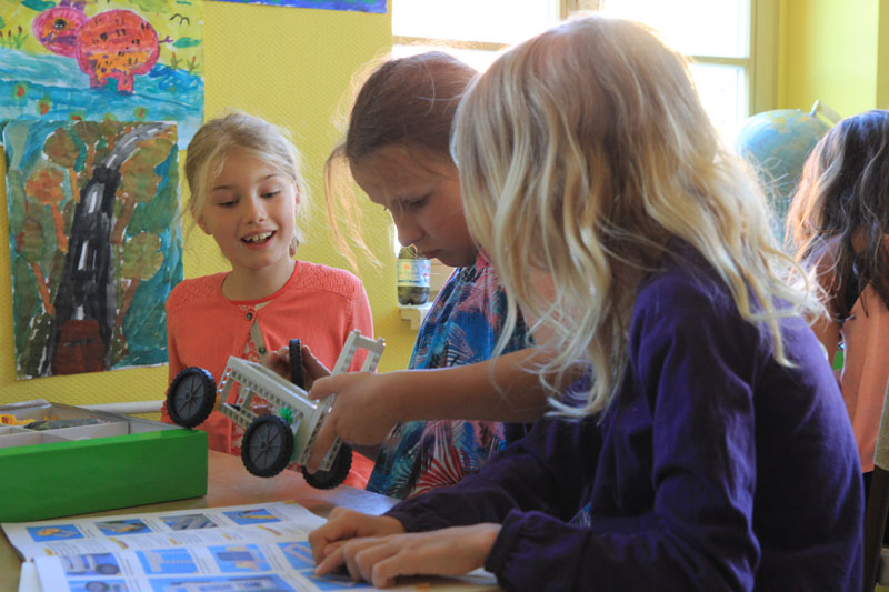 Das Foto zeigt drei Mädchen, die ein Solarauto bauen.