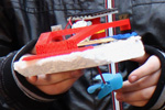 Das Foto zeigt ein kleines Boot, das aus Schaumpolystyrol und Legosteinen gebaut wurde und mit einer Solarzelle, einem Motor und einer Schiffsschraube als Antrieb ausgestattet ist.