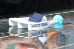 Das Foto zeigt einen kleinen Trimaran, der aus Styropor gebaut wurde und mit einer Solarzelle, einem Motor und einer Schiffsschraube als Antrieb ausgestattet ist.