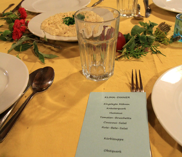 Das Foto zeigt einen Ausschnitt eines festlich gedeckten Tisches. Neben dem Teller liegt ein Menuplan.