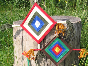 Das Foto zeigt eine Bastelarbeit: Aus Holzstäbchen und farbigem Zwirn wurden Vierecke gestaltet, die an Augen erinnern.