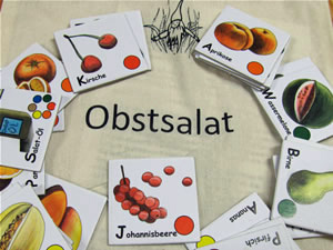 Das Foto zeigt mehrere Memokärtchen, die mit farbigen Zeichnungen  von Früchten bedruckt sind. Diese liegen auf einem Stoffbeutel mit der Aufschrift: Obstsalat.